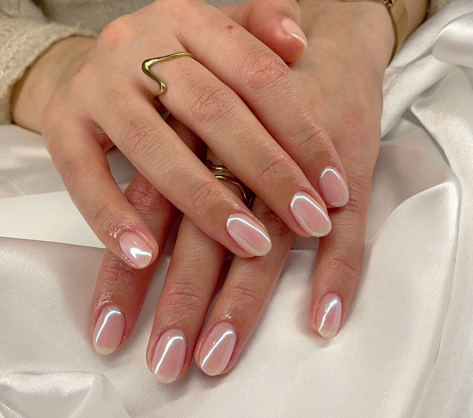 Twee handen met witte micro French nagels op witte satijn