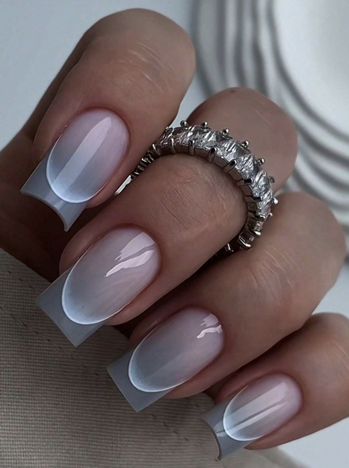 Lange vierkante nagels met een blauwgrijze ombre French en een ring met kristallen